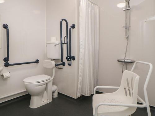 a bathroom with a toilet and two white chairs at Harcombe House Bungalow 9 in Newton Abbot