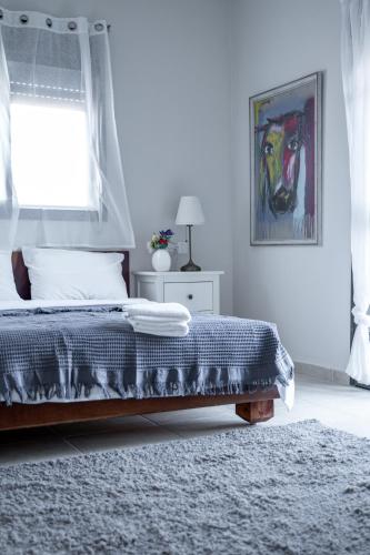a white bedroom with a bed and a window at Ettys Villa in Giv'at Yo'av