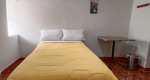 ein großes gelbes Bett in einem Zimmer mit einem Tisch in der Unterkunft Oro Verde Hostal in Cusco