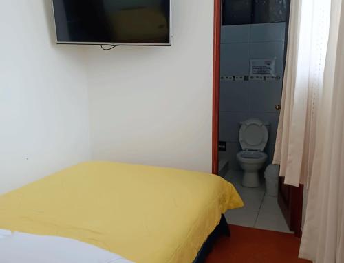 ein Schlafzimmer mit einem gelben Bett und einem WC in der Unterkunft Oro Verde Hostal in Cusco