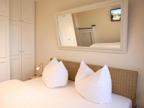 een slaapkamer met witte kussens op een bed met een spiegel bij Kampstraße 9, W6, GB3 in Westerland