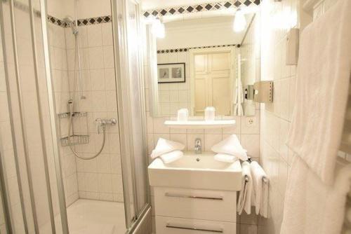 een witte badkamer met een wastafel en een douche bij Kampstraße 9, W6, GB3 in Westerland