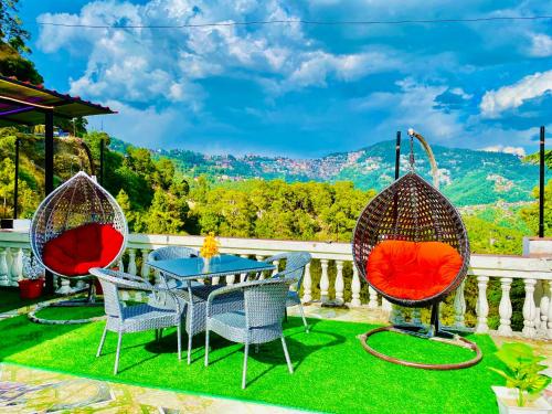 eine Terrasse mit 3 Stühlen und einem Tisch mit Aussicht in der Unterkunft Hotel Tara Regency - A family Hotel in Shimla