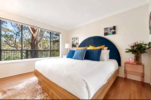 a bedroom with a large bed and a large window at Canto do Sol - 4BR Avoca Getaway in Avoca Beach