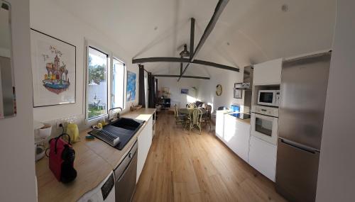 une cuisine avec des armoires blanches et un plancher en bois dans l'établissement Deux maisons reunis par le jardin et sa cabine de plage, à 8min à pieds des plages et de l'océan, à Batz-sur-Mer