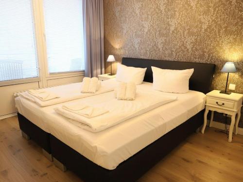 uma cama grande com lençóis brancos e almofadas brancas em Im Zentrum von Westerland gelegene Ferienwohnung mit Westbalkon und schönem Ausblick em Westerland