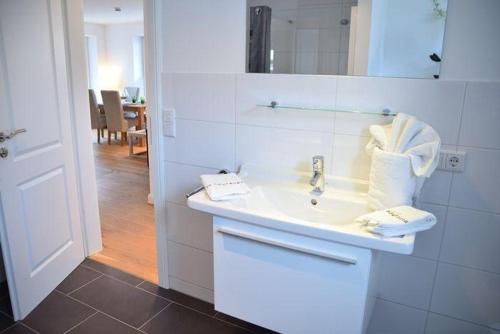 uma casa de banho branca com um lavatório e um espelho em Brandenburger Straße 5a - W15 em Westerland