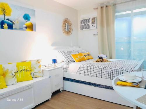a white bedroom with a bed and a table at S&S Condostay in Cagayan de Oro