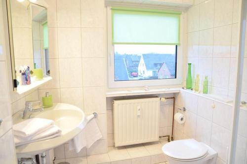 La salle de bains est pourvue d'un lavabo, de toilettes et d'une fenêtre. dans l'établissement Krabbenliebe, à Westerland