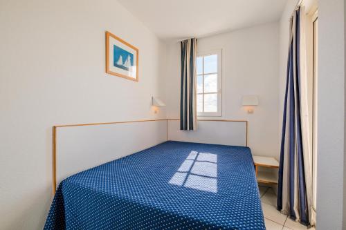 - un lit bleu dans une chambre avec fenêtre dans l'établissement Résidence le Hameau de Cap Esterel - maeva Home - Appartement 2 Pièces 5 Personnes - Confort MAE-1127, à Saint-Raphaël