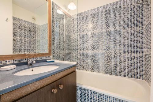 une salle de bain avec un lavabo, une baignoire et un miroir dans l'établissement Résidence le Hameau de Cap Esterel - maeva Home - Appartement 2 Pièces 5 Personnes - Confort MAE-1127, à Saint-Raphaël