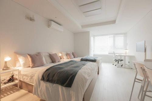 a white bedroom with a large bed and a desk at Mirae stay 67 in Seoul