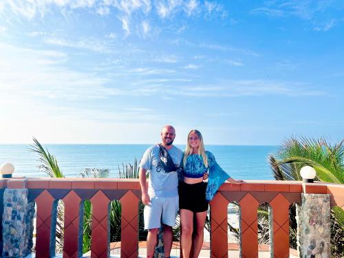 a man and a woman standing on a balcony overlooking the ocean at Sầm Sơn Boutique Hotel Phan Thiết in Phan Thiet