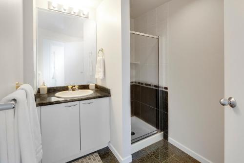 a white bathroom with a sink and a shower at Breathtaking Downtown Condo with Stunning Harbor Views! in Vancouver