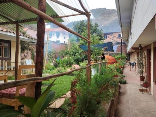 einen Innenhof mit einem Garten und eine Person, die auf einem Gehweg geht in der Unterkunft Samay Wasi Pisac Retreat in Pisac