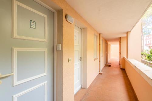 un couloir vide avec une porte et une fenêtre dans l'établissement Résidence le Hameau de Cap Esterel - maeva Home - Appartement 2 Pièces 5 Personnes - Confort MAE-2130, à Saint-Raphaël