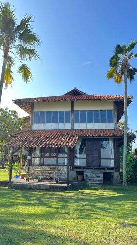 a house with a straw roof and palm trees at Taverno Villa in Serang