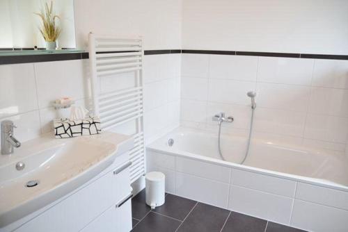een witte badkamer met een bad en een wastafel bij Bomhoffstr. 17, Whg. 20 in Westerland