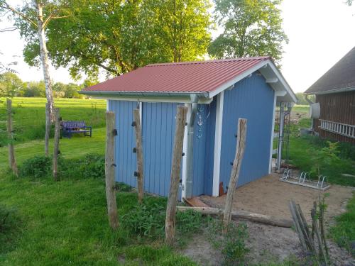 a blue shed with a red roof in a yard at Hütte Krötenhof, Radfahrer Übernachtung in Barförde