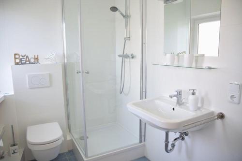 La salle de bains blanche est pourvue d'une douche et d'un lavabo. dans l'établissement Kjeirstr. 34, W5, H. Atlanta, à Westerland