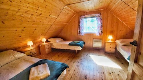 a bedroom with two beds in a wooden cabin at Osada nad Wdą w Borsku in Borsk