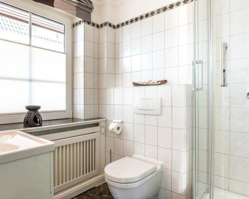 ein weißes Bad mit einem WC und einem Waschbecken in der Unterkunft Kampstraße 9, W4, GB3 in Westerland