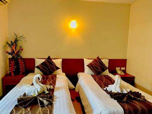 a hotel room with two beds with swans on them at Authong Residence in North Pattaya