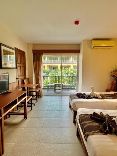 a hotel room with three beds and a balcony at Authong Residence in North Pattaya