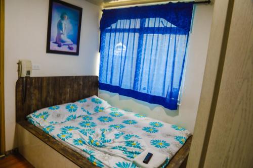 Dormitorio pequeño con cama y ventana azul en Hotel Residencial Olaya Plaza, en Manizales