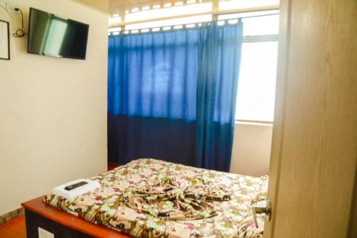 1 dormitorio con 1 cama con cortina azul en Hotel Residencial Olaya Plaza, en Manizales