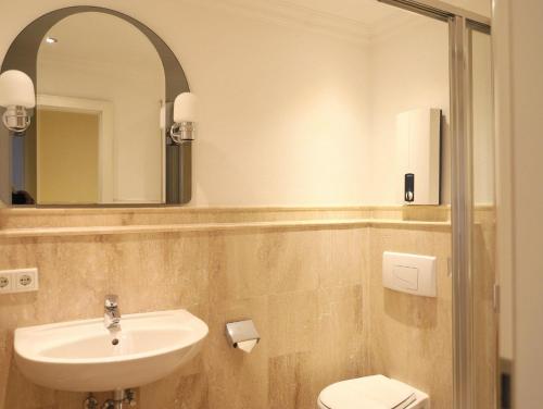 een badkamer met een wastafel, een toilet en een spiegel bij 2-Zimmer-Appartementin zentraler Lage in Westerland