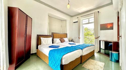 a bedroom with a bed with a blue blanket at Royal Pearl Hills (Pvt) Ltd. in Nuwara Eliya