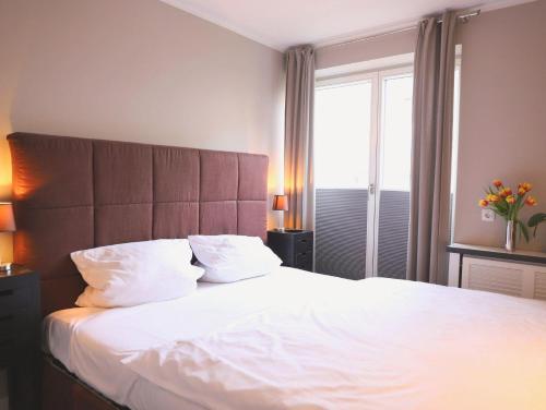 Schlafzimmer mit einem Bett mit weißer Bettwäsche und einem Fenster in der Unterkunft Ferienhaus mit neuen und sehr hochwertigen Appartements in zentraler Lage in Westerland in Westerland