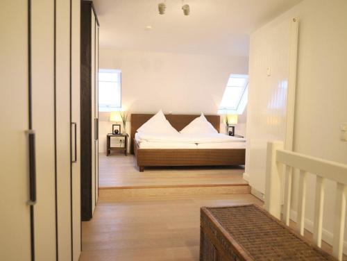 1 Schlafzimmer mit einem Bett mit weißer Bettwäsche und 2 Fenstern in der Unterkunft Viktoriastraße 6 Whg.19 in Westerland