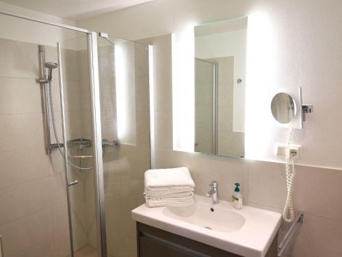 La salle de bains est pourvue d'un lavabo et d'une douche avec un miroir. dans l'établissement Viktoriastraße 6 Whg.19, à Westerland