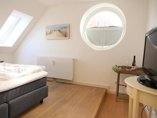 Schlafzimmer mit einem Bett und einem runden Fenster in der Unterkunft Ferienhaus mit neuen und sehr hochwertigen Appartements in zentraler Lage in Westerland in Westerland