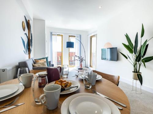 a table with plates of food on it in a living room at Modern Apartments with Balcony in Merton near Wimbledon by Sojo Stay in Mitcham