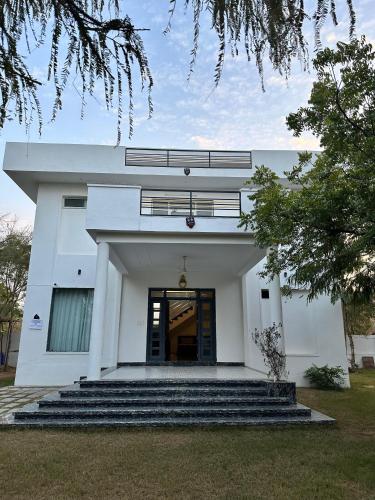 ein weißes Gebäude mit einer Treppe davor in der Unterkunft namastay farm in Jaipur