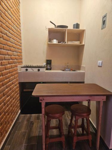 cocina con mesa, 2 taburetes y fregadero en Gardenias 4, en Zacatlán
