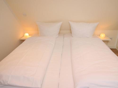 ヴェニングシュテットにあるSüder Wung 12, Whg. 3の白い枕付きの大型ベッド1台が備わります。