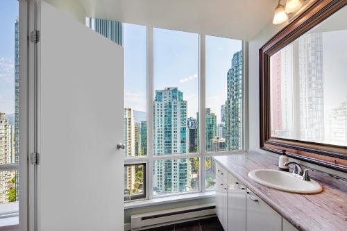 a bathroom with a sink and large windows at Designer sub-penthouse - Central Downtown Views And King Bed! in Vancouver