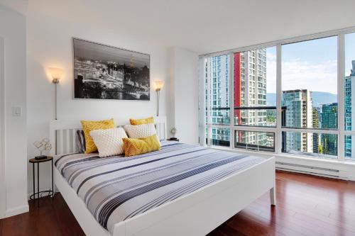 Designer sub-penthouse - Central Downtown Views And King Bed! في فانكوفر: غرفة نوم بيضاء مع سرير كبير ونوافذ كبيرة
