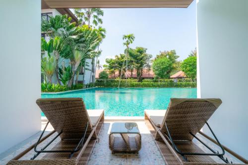 two chairs sitting next to a swimming pool at Estella Phuket Mai Khao Beach Resort in Mai Khao Beach