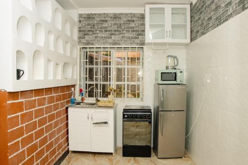 Il dispose d'une cuisine avec un réfrigérateur et un mur en briques. dans l'établissement House - King Beds - 5G Wi-Fi - Hottub -PS4, à Dar es Salaam