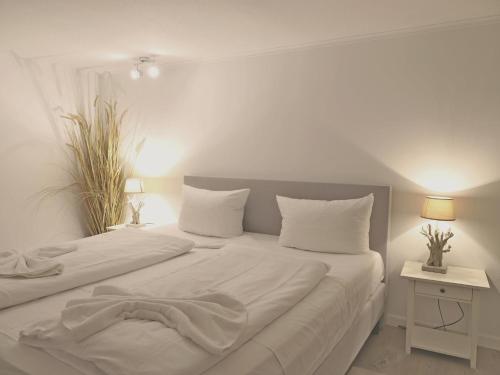 een witte slaapkamer met een groot bed met witte lakens bij -Zimmer-Appartement über 2 Etagen in Wenningstedt in ruhiger Lage in Wenningstedt