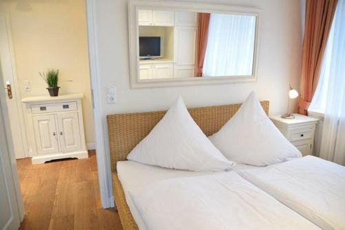 1 dormitorio con 1 cama con sábanas blancas y espejo en Kampstraße 9, W3, GB3 en Westerland