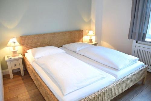 1 cama grande con sábanas blancas y almohadas. en Bundiswung 9 Whg. 2, GB2, en Westerland