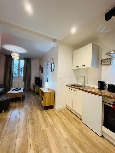 une cuisine avec des armoires blanches et un salon dans l'établissement Le cocon Fécamp, à Fécamp