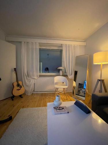 a living room with a table and a chair and a guitar at Cozy lake view room by city center in Kuopio