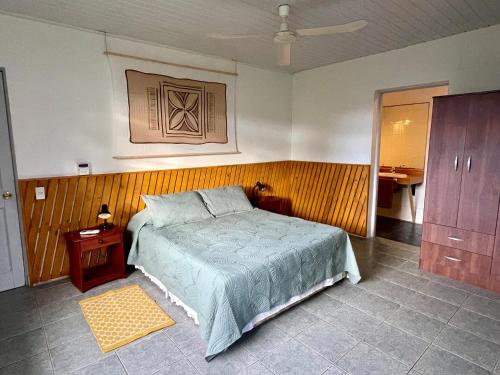 a bedroom with a bed and a wooden wall at Manureva Nui Hotel Boutique in Hanga Roa